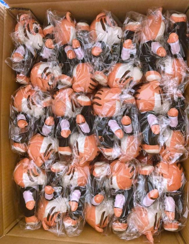 A bulk run of the tiger mascot plush in a tailored vest, bagged and boxed ready for dispatch