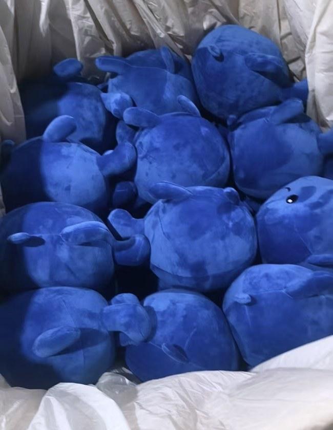 A bulk run of the rounded blue character soft toys, bagged in cartons ready for dispatch